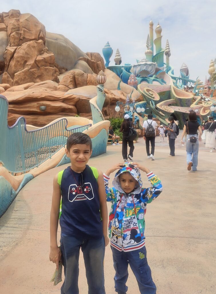 Vihaan and Mehaank standing together on a walkway in front of a whimsical blue fantasy structure