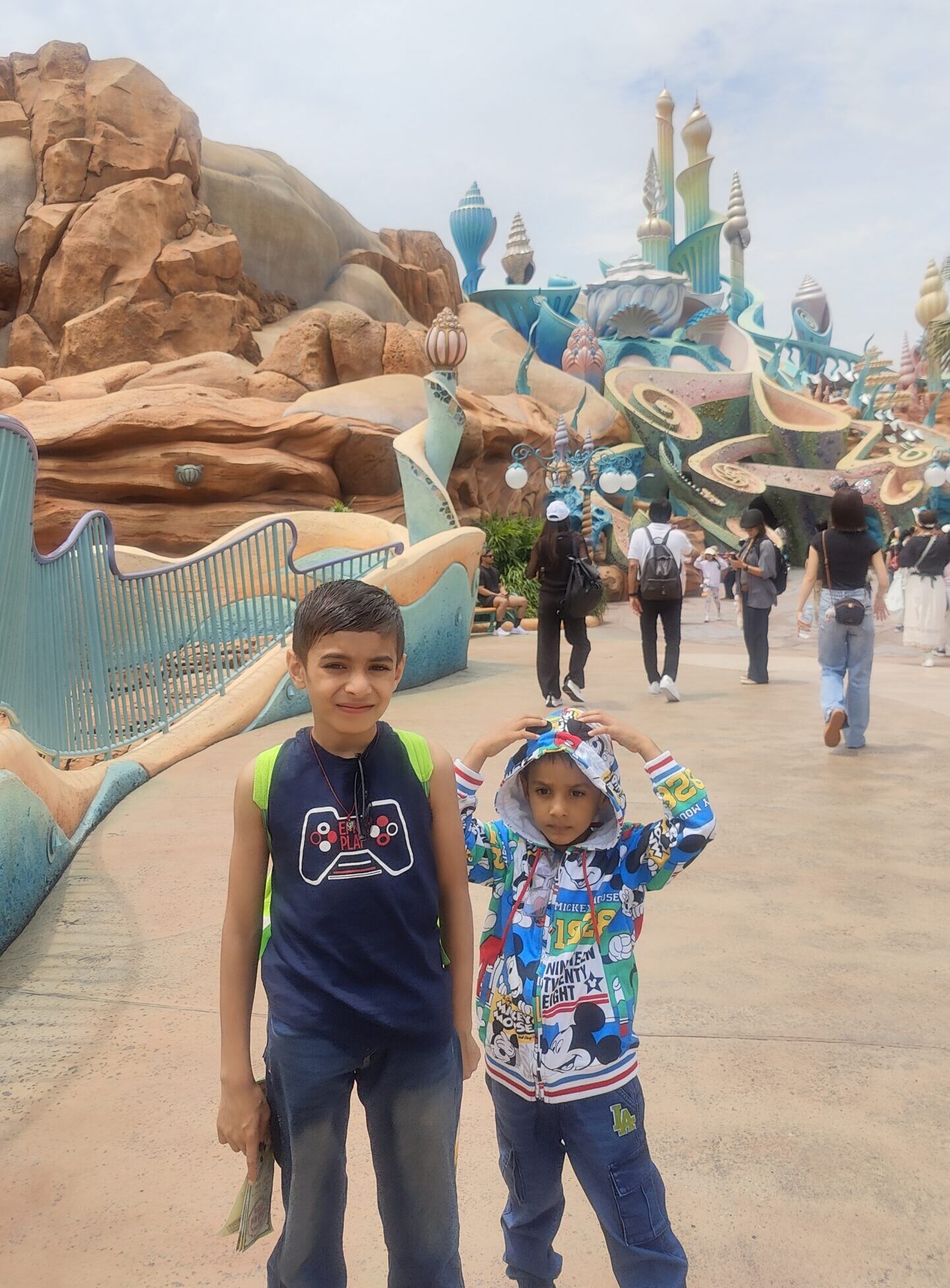 Vihaan and Mehaank standing together on a walkway in front of a whimsical blue fantasy structure
